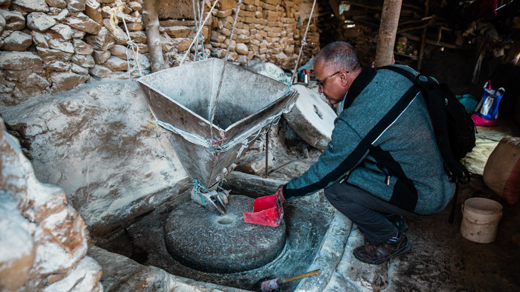 Nepal native Suman Basnet, senior strategic adviser for the Integrated Watershed Management Activity, inspects a water mill. These mills traditionally have wooden paddles, but many are being replaced by modern steel turbines, dramatically increasing efficiency. Photo: Pramin Manandhar