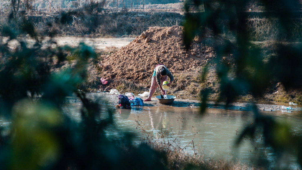 A Nepali woman uses a stream to wash clothes. Photo: Pramin Manandhar