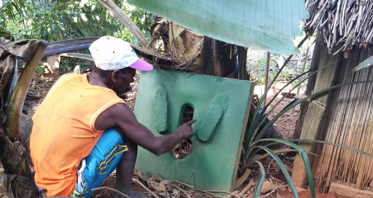 A local mason examines a SanPlat latrine slab in Amboditafara, Madagascar. Photo credit: Water CKM Project