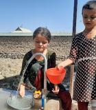 Children fill water from Ms. Sonia Rajabova’s self-constructed water stand. May, 2022. Credit: USAID/Tajikistan