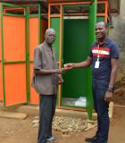 In Abidjan, Cote d’Ivoire, a landlord received the key to a new nine-block latrine for his compound. Photo credit: PSI/USAID SSD Project